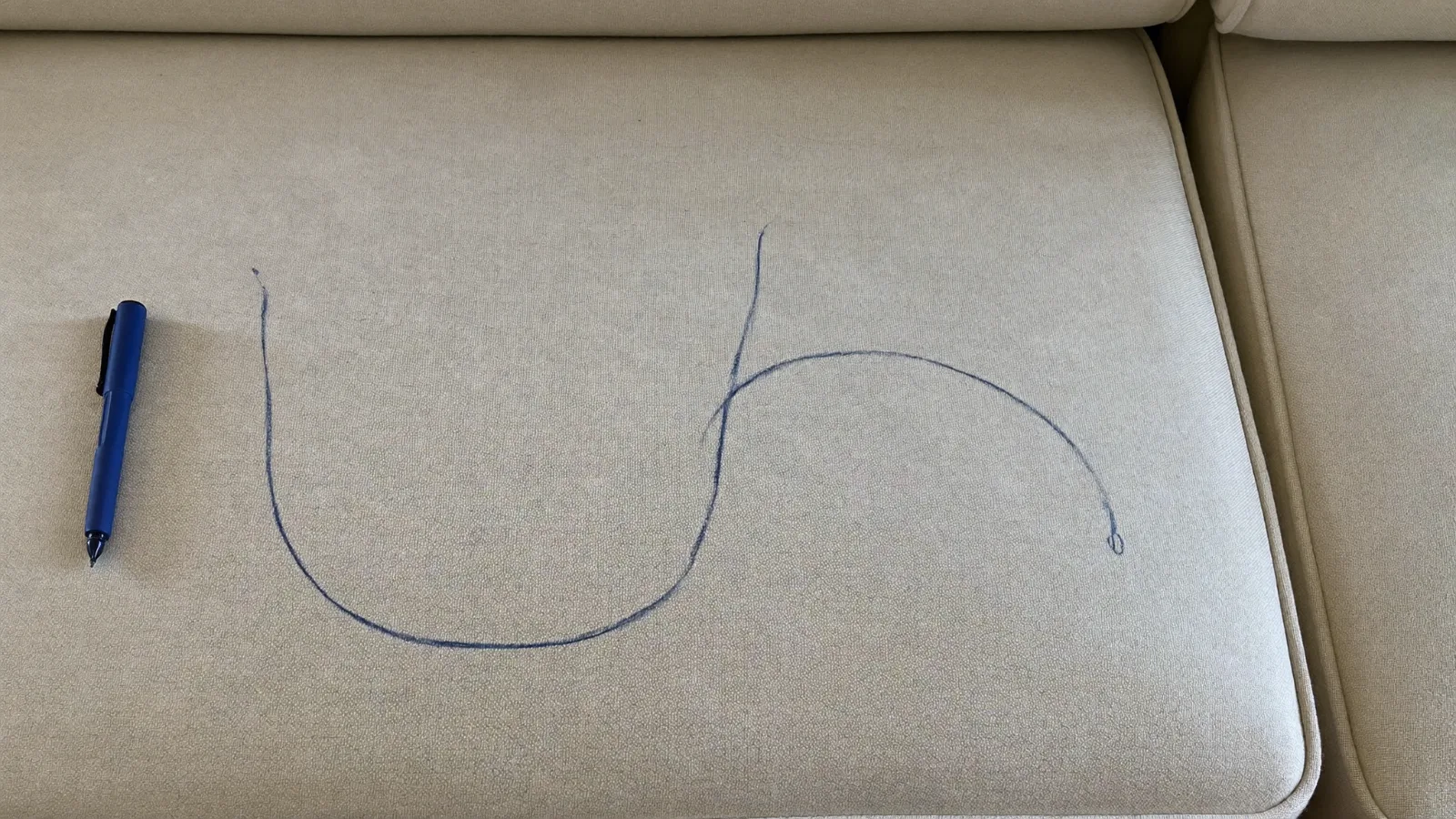 Tache de stylo sur le canapé : trait d encre bleue sur tissu clair — illustration